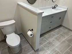 New toilet, toilet paper holder, and half wall for some privacy.