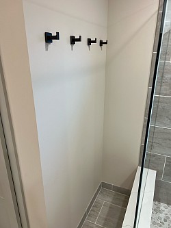 Towel and robe hooks on the outside wall of the linen closet next to the shower.